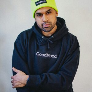 A man in a black hoodie and neon yellow beanie.