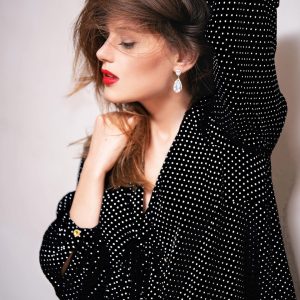 A confident woman in a black polka dotted top and striking red lipstick.