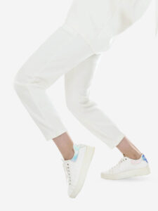 A woman in white sweats, sneakers, and high-rise white jeans.